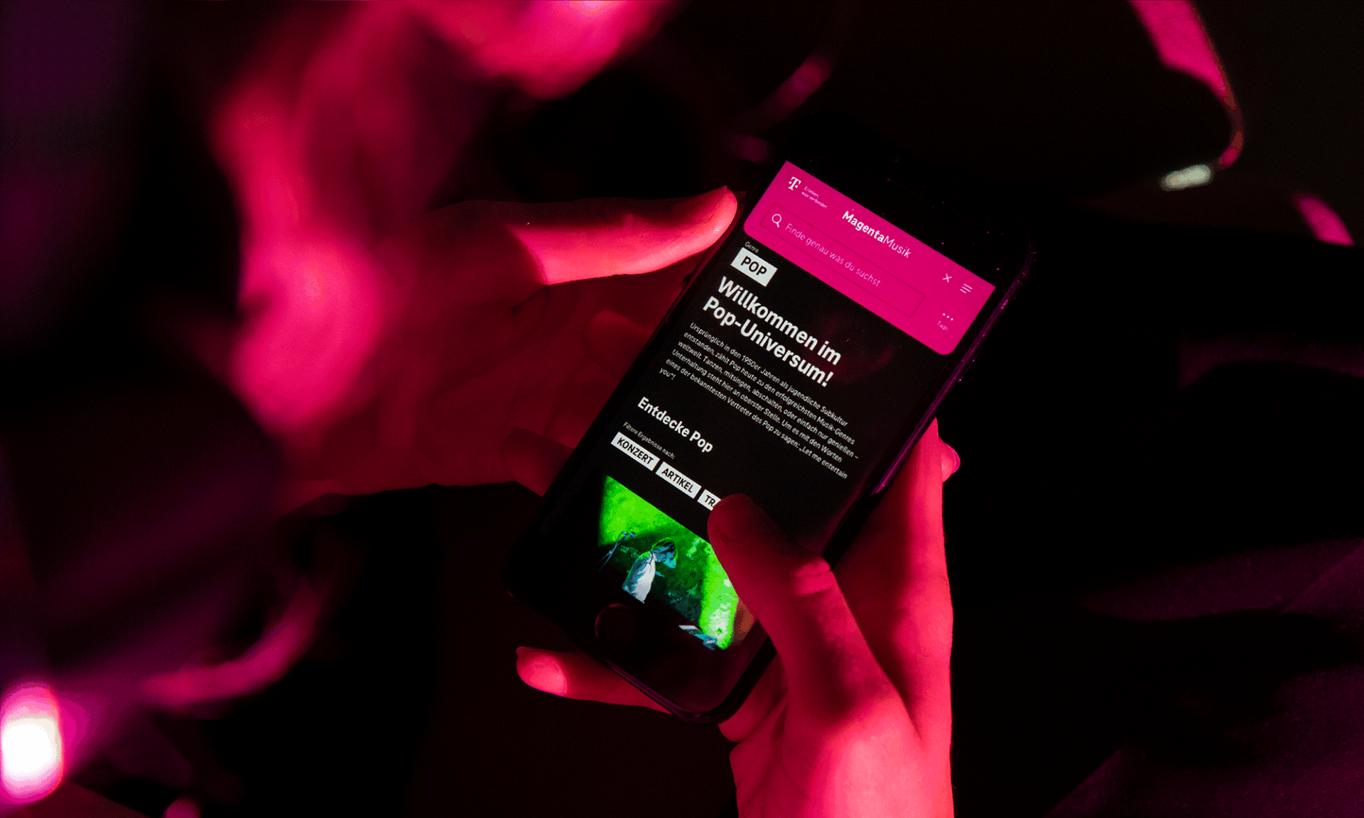 Eine Person schaut sich eine Landing Page von Magenta Music auf dem Handy Display an